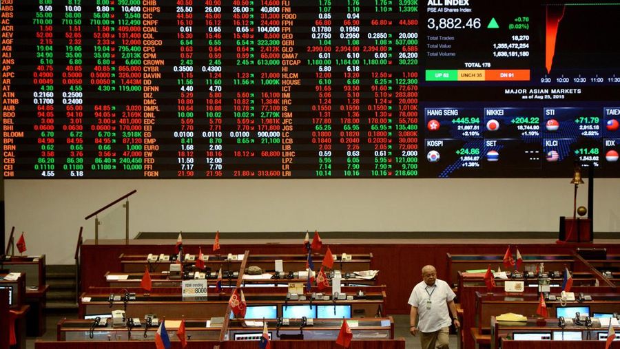 A trader (bottom R) walks in front of the main electronic board at the Philippine Stock Exchange in Manila on August 25, 2015. Asian markets were mixed after a seesaw session on August 25, with Tokyo diving and Shanghai extending its worst rout in almost 20 years, while other regional markets bounced into positive territory.      AFP PHOTO / NOEL CELIS        (Photo credit should read NOEL CELIS/AFP via Getty Images)