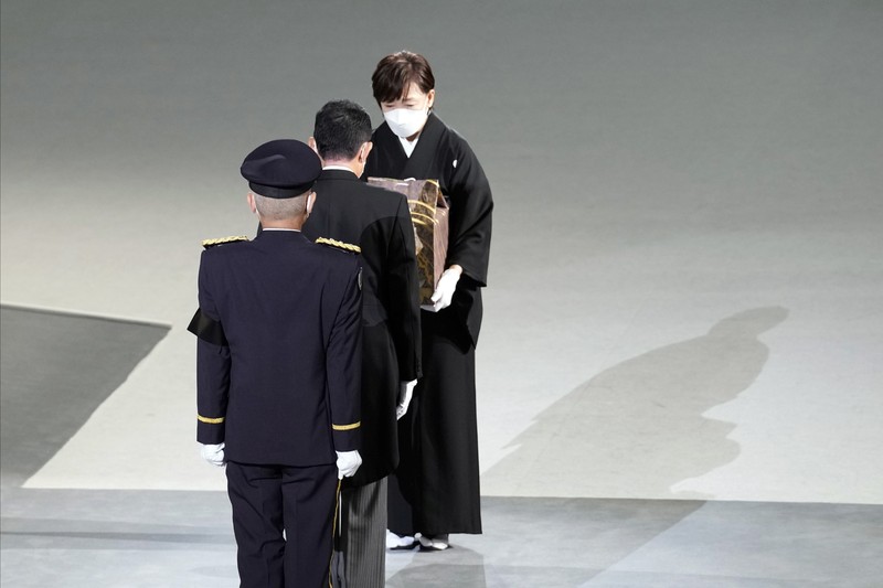 Abu Mantan Perdana Menteri Jepang Shinzo Abe Saat Pemakaman Kenegaraan Istri mantan Perdana Menteri Jepang Shinzo Abe, Akie membawa abu suaminya saat tiba untuk memulai pemakaman kenegaraannya di Nippon Budokan di Tokyo, Jepang, Selasa (27/9/2022). Pemerintah Jepang menghabiskan biaya sebesar 1,65 miliar Yen (Rp 173 miliar) untuk pemakaman kenegaraan Abe, yang mencakup 800 juta Yen (Rp 83,9 miliar) untuk keamanan dan 600 juta Yen (Rp 62,9 miliar) untuk menjamu delegasi asing. (Philip Fong/Pool Photo via AP)