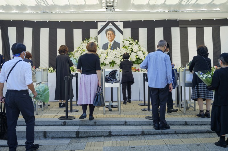 Orang-orang meninggalkan bunga dan memberi penghormatan kepada mantan Perdana Menteri Jepang Shinzo Abe di luar Nippon Budokan di Tokyo, Jepang Selasa (27/9/2022). Diperkirakan 4.300 orang akan menghadiri seremoni pemakaman kenegaraan ini, dengan sedikitnya 48 pemimpin atau pejabat tinggi pemerintahan berbagai negara, baik yang masih aktif menjabat maupun yang sudah tidak menjabat, akan turut hadir. (Nicolas Datiche/Pool Photo via AP)