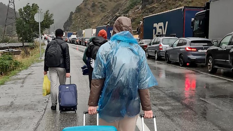 Sejumlah warga Rusia berjalan setelah melintasi perbatasan di Verkhny Lars antara Georgia dan Rusia di Georgia, Selasa (27/9/2022). Mereka keluar dari negaranya untuk menghindari dipanggil untuk ikut dalam perang di Ukraina yang tidak mereka setujui. (AP Photo/Zurab Tsertsvadze)