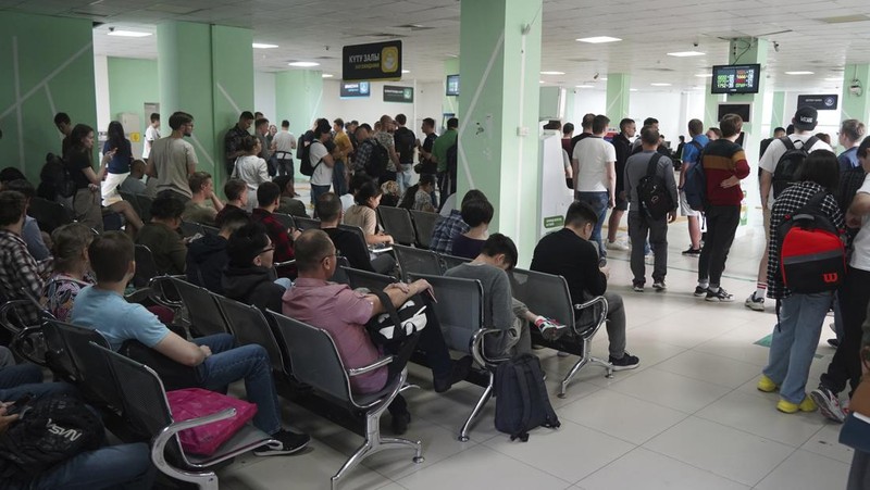 Sejumlah warga Rusia berjalan setelah melintasi perbatasan di Verkhny Lars antara Georgia dan Rusia di Georgia, Selasa (27/9/2022). Mereka keluar dari negaranya untuk menghindari dipanggil untuk ikut dalam perang di Ukraina yang tidak mereka setujui. (AP Photo/Zurab Tsertsvadze)
