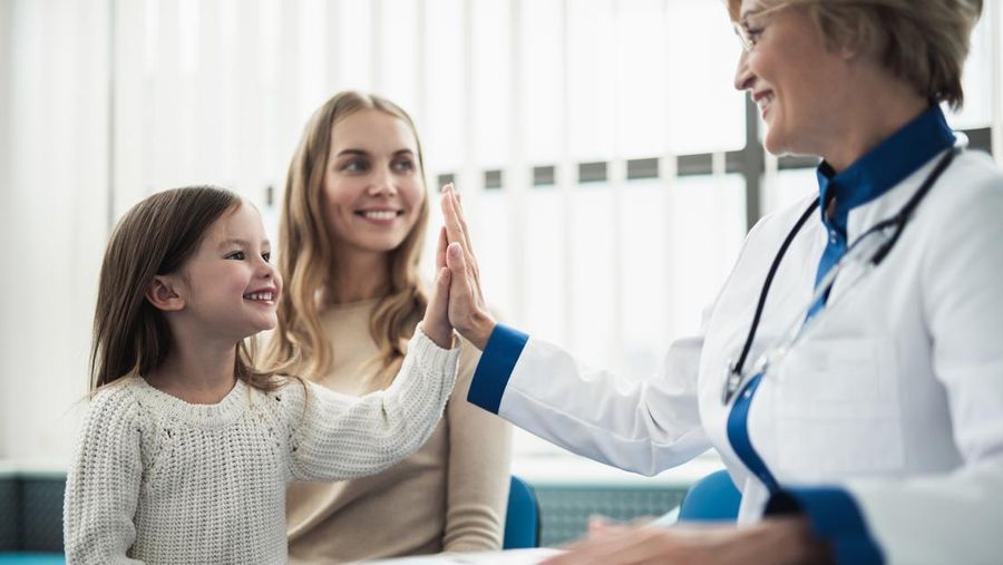 Concept of trustworthy method of consultation in healthcare system. Waist up portrait of smiling little girl giving five to pediatrician lady in medical cabinet