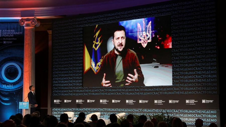 Orang-orang menonton Presiden Ukraina Volodymyr Zelensky yang terlihat di layar saat dia berbicara, selama Forum Demokrasi Athena, di Zappeion Hall di Athena, Yunani,, Rabu (28/9/2022). (REUTERS/Louiza Vradi)