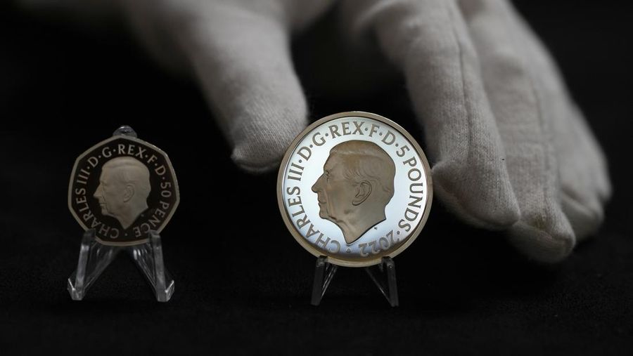 Two new coins bearing official coinage portrait of King Charles III, on the left is the new 50 pence coin, and right is the new 5 pound commemorative coin, which will be among the first coins to bear the new king's head, during a press preview in London, Thursday, Sept. 29, 2022. The likeness of the king was created by British sculptor Martin Jennings, and approved by the king. (AP Photo/Alastair Grant)