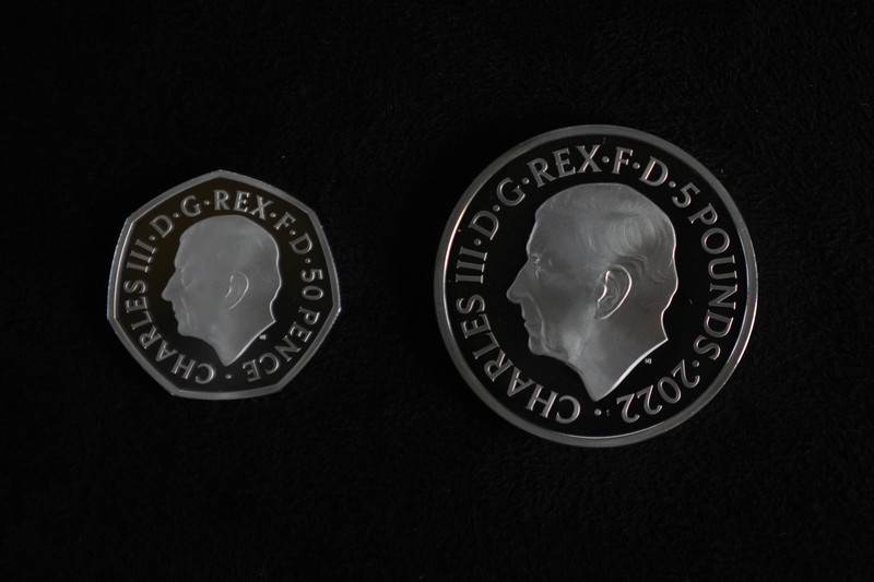 Britain Royals Two new coins bearing official coinage portrait of King Charles III, on the left is the new 50 pence coin, and right is the new 5 pound commemorative coin, which will be among the first coins to bear the new king's head, during a press preview in London, Thursday, Sept. 29, 2022. The likeness of the king was created by British sculptor Martin Jennings, and approved by the king. (AP Photo/Alastair Grant)