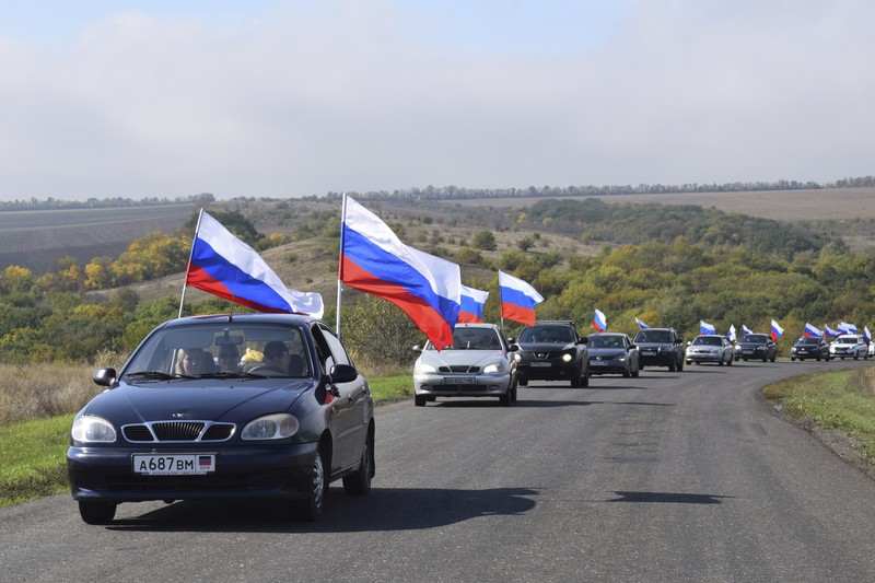Russia Ukraine People wave Russian national flags as they gather during celebrations marking the annexation of the Luhansk region into Russia in Luhansk, Ukraine, Friday, Sept. 30, 2022. The signing of the treaties making the four annexed regions part of Russia follows the completion of the Kremlin-orchestrated