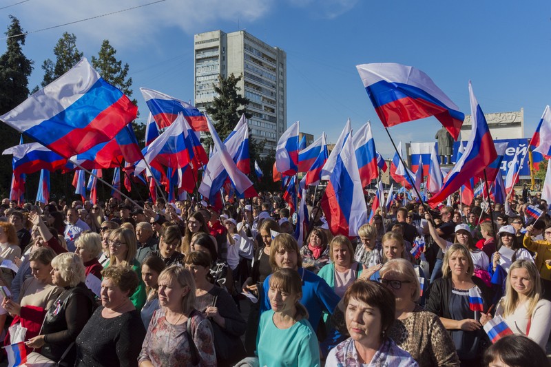 People wave Russian national flags as they gather during celebrations marking the annexation of the Luhansk region into Russia in Luhansk, Ukraine, Friday, Sept. 30, 2022. The signing of the treaties making the four annexed regions part of Russia follows the completion of the Kremlin-orchestrated 