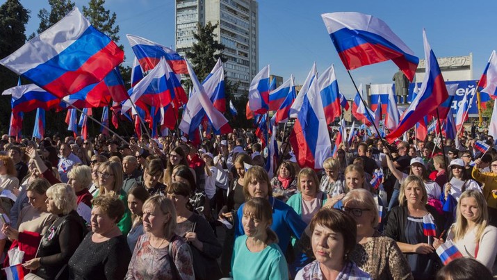 Russia Ukraine People wave Russian national flags as they gather during celebrations marking the annexation of the Luhansk region into Russia in Luhansk, Ukraine, Friday, Sept. 30, 2022. The signing of the treaties making the four regions part of Russia follows the completion of the Kremlin-orchestrated