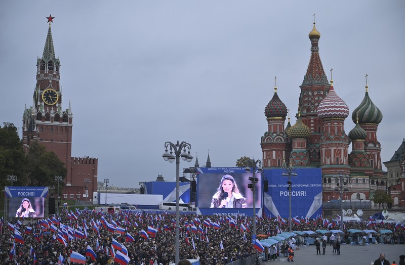People wave Russian national flags as they gather during celebrations marking the annexation of the Luhansk region into Russia in Luhansk, Ukraine, Friday, Sept. 30, 2022. The signing of the treaties making the four annexed regions part of Russia follows the completion of the Kremlin-orchestrated 
