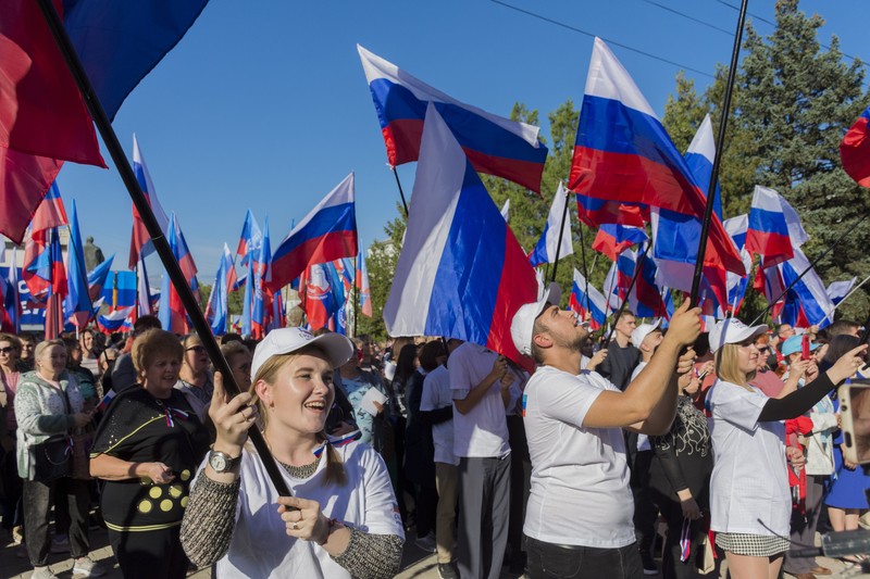 People wave Russian national flags as they gather during celebrations marking the annexation of the Luhansk region into Russia in Luhansk, Ukraine, Friday, Sept. 30, 2022. The signing of the treaties making the four annexed regions part of Russia follows the completion of the Kremlin-orchestrated 