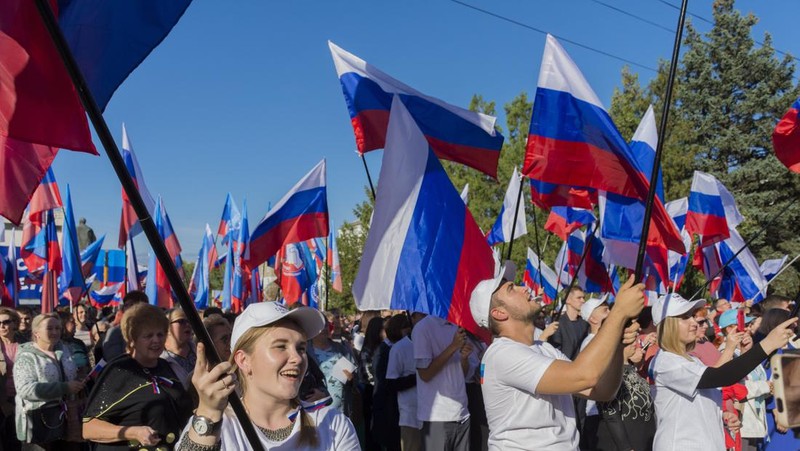 People wave Russian national flags as they gather during celebrations marking the annexation of the Luhansk region into Russia in Luhansk, Ukraine, Friday, Sept. 30, 2022. The signing of the treaties making the four annexed regions part of Russia follows the completion of the Kremlin-orchestrated 