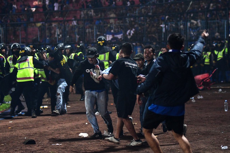 This picture taken on October 1, 2022 shows security personnel (lower) on the pitch after a football match between Arema FC and Persebaya Surabaya at Kanjuruhan stadium in Malang, East Java. - At least 127 people died at a football stadium in Indonesia late on October 1 when fans invaded the pitch and police responded with tear gas, triggering a stampede, officials said. (Photo by AFP) (Photo by STR/AFP via Getty Images)