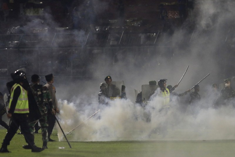 Indonesia Soccer Deaths Plain-clothed officers stand near the wreckage of police vehicles damaged during a clash between supporters of two Indonesian soccer teams at Kanjuruhan Stadium in Malang, East Java, Indonesia, Saturday, Oct. 1, 2022. Panic following police actions left over 100 dead, mostly trampled to death, police said Sunday. (AP Photo/Yudha Prabowo)