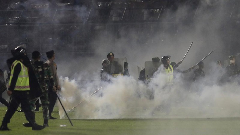 Plain-clothed officers stand near the wreckage of police vehicles damaged during a clash between supporters of two Indonesian soccer teams at Kanjuruhan Stadium in Malang, East Java, Indonesia, Saturday, Oct. 1, 2022. Panic following police actions left over 100 dead, mostly trampled to death, police said Sunday. (AP Photo/Yudha Prabowo)