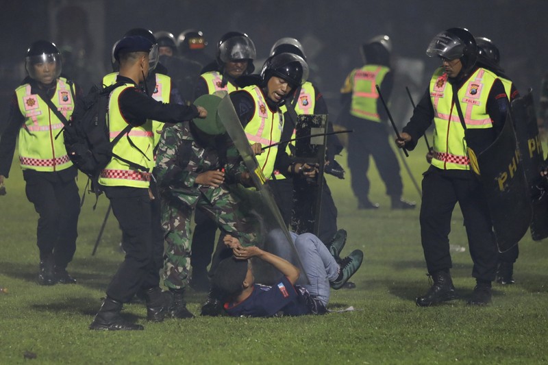 Indonesia Soccer Deaths Plain-clothed officers stand near the wreckage of police vehicles damaged during a clash between supporters of two Indonesian soccer teams at Kanjuruhan Stadium in Malang, East Java, Indonesia, Saturday, Oct. 1, 2022. Panic following police actions left over 100 dead, mostly trampled to death, police said Sunday. (AP Photo/Yudha Prabowo)