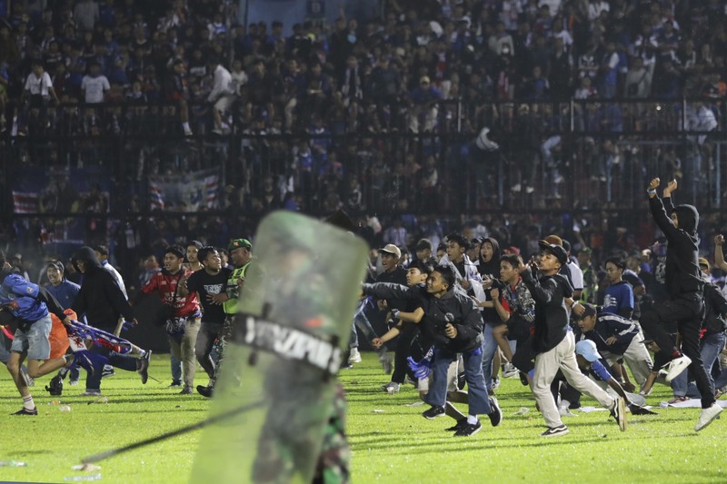 Indonesia Soccer Deaths Plain-clothed officers stand near the wreckage of police vehicles damaged during a clash between supporters of two Indonesian soccer teams at Kanjuruhan Stadium in Malang, East Java, Indonesia, Saturday, Oct. 1, 2022. Panic following police actions left over 100 dead, mostly trampled to death, police said Sunday. (AP Photo/Yudha Prabowo)