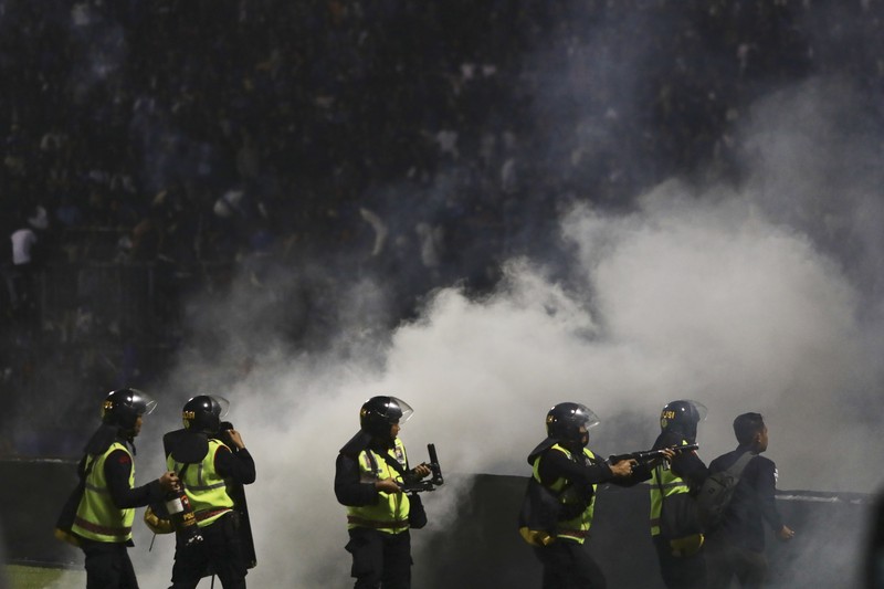 Indonesia Soccer Deaths Plain-clothed officers stand near the wreckage of police vehicles damaged during a clash between supporters of two Indonesian soccer teams at Kanjuruhan Stadium in Malang, East Java, Indonesia, Saturday, Oct. 1, 2022. Panic following police actions left over 100 dead, mostly trampled to death, police said Sunday. (AP Photo/Yudha Prabowo)