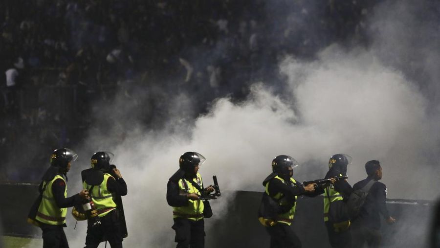 Police officers fire tear gas during clashes between fans at a soccer match at Kanjuruhan Stadium in Malang, East Java, Indonesia, Saturday, Oct. 1, 2022. Panic following police actions left over 100 dead, mostly trampled to death, police said Sunday. (AP Photo/Yudha Prabowo)