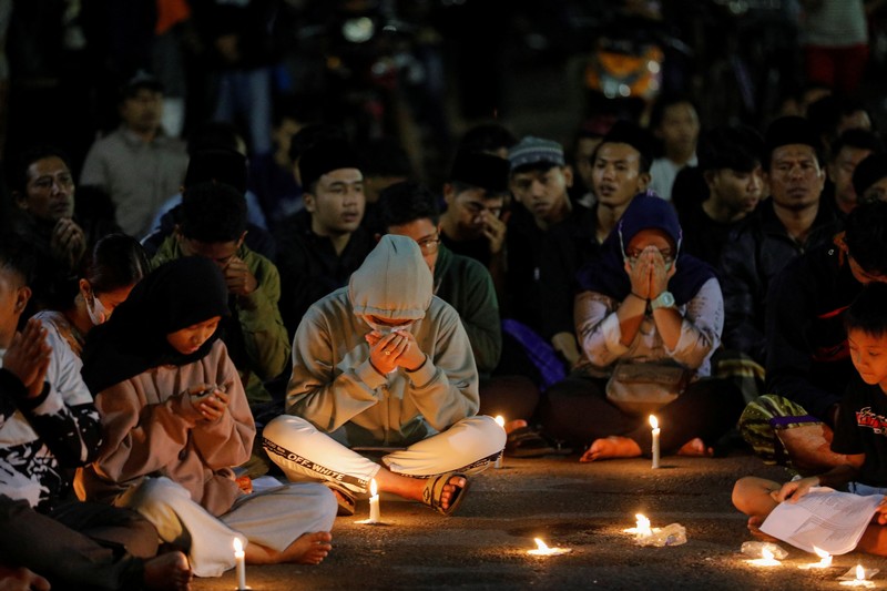Arema football club supporters take part on a vigil outside the Kanjuruhan stadium to pay condolence to the victims, after a riot and stampede following soccer match between Arema vs Persebaya outside in Malang, East Java province, Indonesia, October 2, 2022. REUTERS/Willy Kurniawan