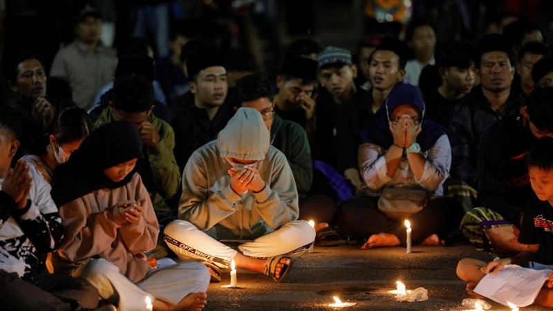 Arema football club supporters take part on a vigil outside the Kanjuruhan stadium to pay condolence to the victims, after a riot and stampede following soccer match between Arema vs Persebaya outside in Malang, East Java province, Indonesia, October 2, 2022. REUTERS/Willy Kurniawan