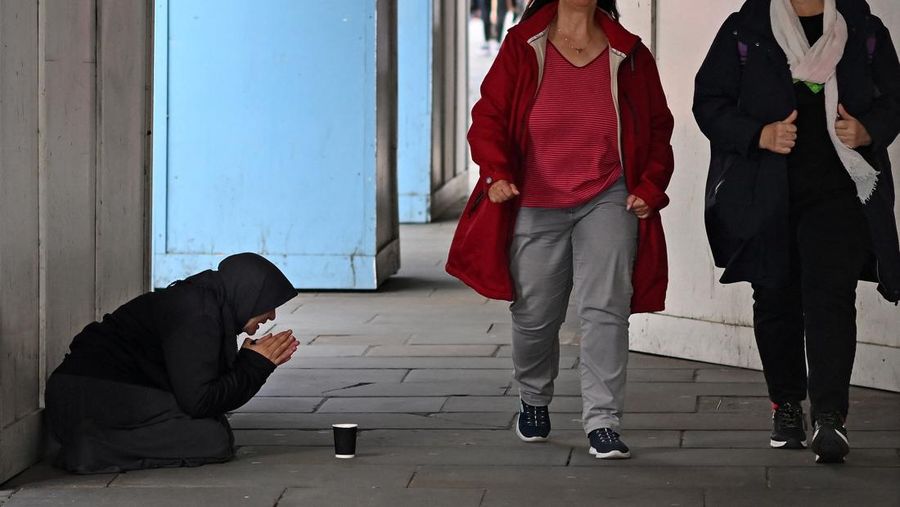 A person kneeling on the pavement begs for money on The Strand in central London on October 1, 2022, as campaigners gather in the city to protest against the cost of living crisis. (Photo by Justin TALLIS / AFP) (Photo by JUSTIN TALLIS/AFP via Getty Images)