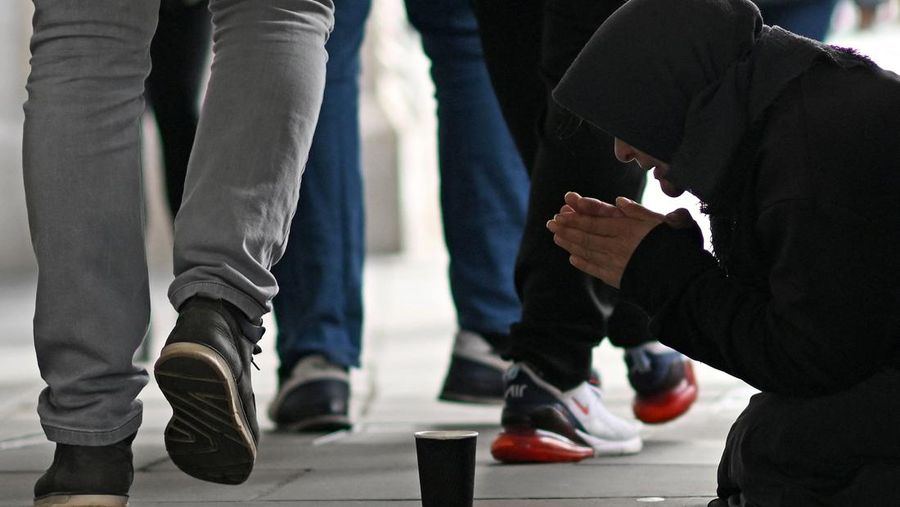 A person kneeling on the pavement begs for money on The Strand in central London on October 1, 2022, as campaigners gather in the city to protest against the cost of living crisis. (Photo by Justin TALLIS / AFP) (Photo by JUSTIN TALLIS/AFP via Getty Images)