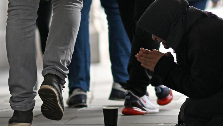 1243643153 A person kneeling on the pavement begs for money on The Strand in central London on October 1, 2022, as campaigners gather in the city to protest against the cost of living crisis. (Photo by Justin TALLIS / AFP) (Photo by JUSTIN TALLIS/AFP via Getty Images)