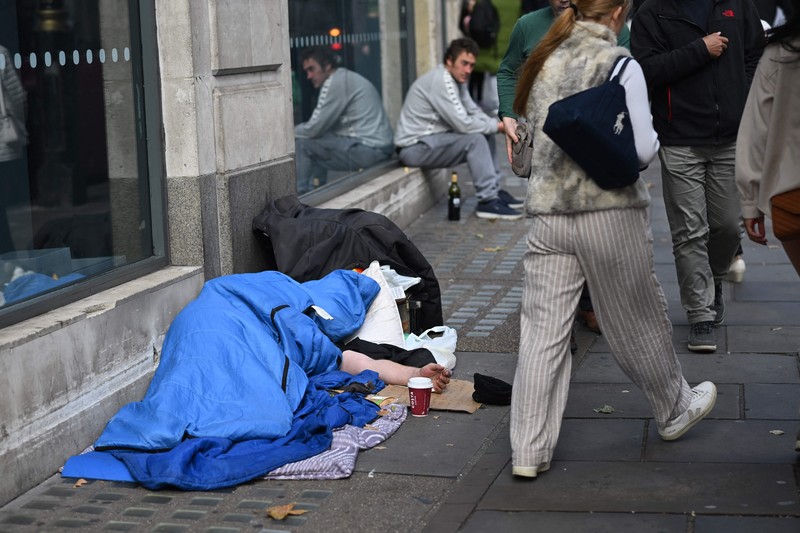 1243639948 A homeless man sleeps in his sleeping bag on The Strand in central London on October 1, 2022, as campaigners gather in the city to protest against the cost of living crisis. (Photo by JUSTIN TALLIS / AFP) (Photo by JUSTIN TALLIS/AFP via Getty Images)