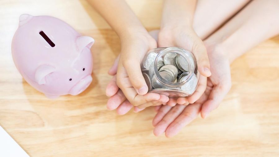 close up of Girl and her mother hold cash and money bottle and there is a pink piggy bank on table