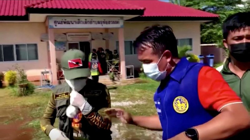 In this image taken from video, officials enter the site of an attack at a daycare canter, Thursday, Oct. 6, 2022, in the town of Nongbua Lamphu, north eastern Thailand. More than 30 people, primarily children, were killed Thursday when a gunman opened fire the childcare center authorities said. (TPBS via AP)