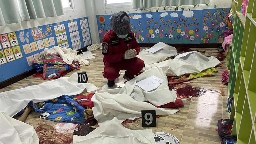 A first responder prays over one of numerous bodies at the site of an attack in a day care center, Thursday, Oct. 6, 2022, in the town of Nongbua Lamphu, north eastern Thailand. A former policeman facing a drug charge burst into a day care center in northeastern Thailand on Thursday, killing dozens of preschoolers and teachers before shooting more people as he fled in the deadliest rampage in the nation’s history. (Mungkorn Sriboonreung Rescue Group via AP)