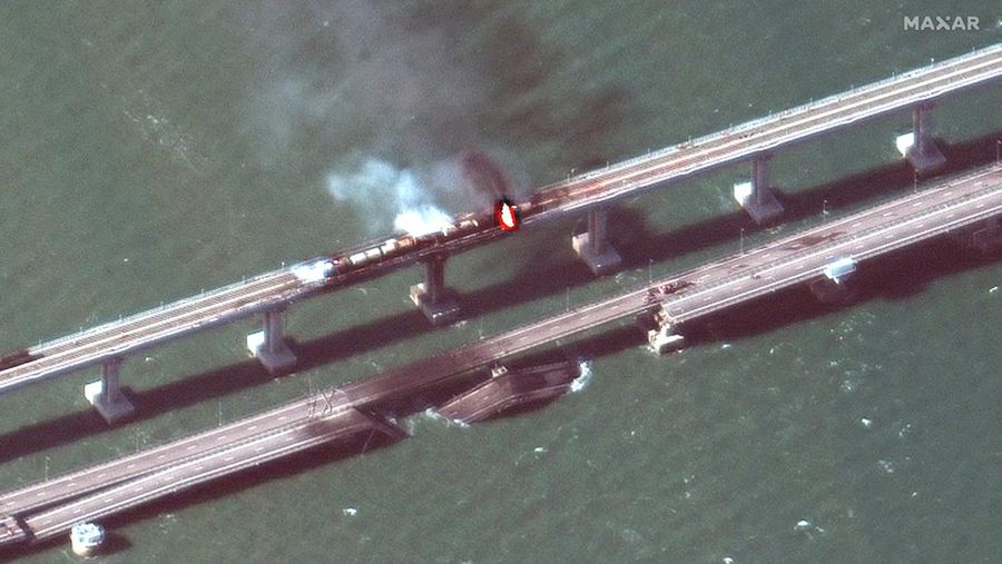Gambar satelit memperlihatkan asap mengepul dari kebakaran di jembatan Kerch di Selat Kerch, Crimea, Sabtu (8/10/2022). Jembatan yang menghubungkan Crimea dengan daratan Rusia itu hancur usai tangki berisi bahan bakar minyak (BBM) diduga meledak di lokasi itu dan menyebabkan 3 orang meninggal. (Maxar Technologies/Handout via REUTERS)