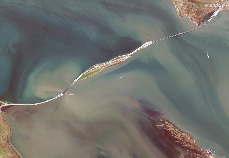 Gambar satelit menunjukkan asap mengepul dari kebakaran di jembatan Kerch di Selat Kerch, Crimea, Sabtu (8/10/2022). Jembatan yang menghubungkan Crimea dengan daratan Rusia itu hancur usai tangki berisi bahan bakar minyak (BBM) diduga meledak di lokasi itu dan menyebabkan 3 orang meninggal. (Maxar Technologies/Handout via REUTERS)