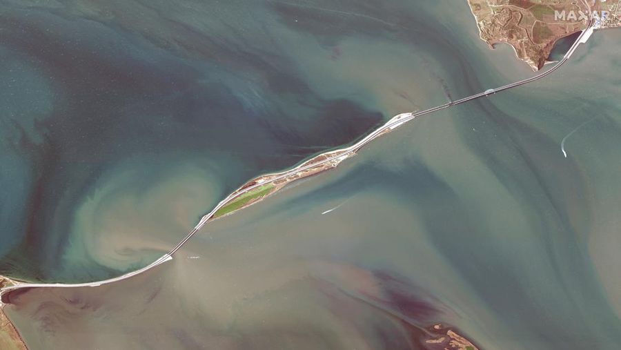 Gambar satelit menunjukkan asap mengepul dari kebakaran di jembatan Kerch di Selat Kerch, Crimea, Sabtu (8/10/2022). Jembatan yang menghubungkan Crimea dengan daratan Rusia itu hancur usai tangki berisi bahan bakar minyak (BBM) diduga meledak di lokasi itu dan menyebabkan 3 orang meninggal. (Maxar Technologies/Handout via REUTERS)