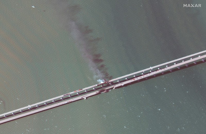 Gambar satelit menunjukkan asap mengepul dari kebakaran di jembatan Kerch di Selat Kerch, Crimea, Sabtu (8/10/2022). Jembatan yang menghubungkan Crimea dengan daratan Rusia itu hancur usai tangki berisi bahan bakar minyak (BBM) diduga meledak di lokasi itu dan menyebabkan 3 orang meninggal. (Maxar Technologies/Handout via REUTERS)