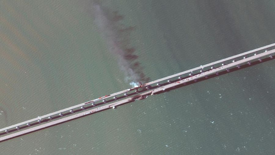 Gambar satelit menunjukkan asap mengepul dari kebakaran di jembatan Kerch di Selat Kerch, Crimea, Sabtu (8/10/2022). Jembatan yang menghubungkan Crimea dengan daratan Rusia itu hancur usai tangki berisi bahan bakar minyak (BBM) diduga meledak di lokasi itu dan menyebabkan 3 orang meninggal. (Maxar Technologies/Handout via REUTERS)