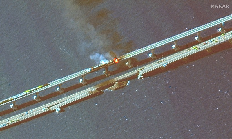 Gambar satelit menunjukkan asap mengepul dari kebakaran di jembatan Kerch di Selat Kerch, Crimea, Sabtu (8/10/2022). Jembatan yang menghubungkan Crimea dengan daratan Rusia itu hancur usai tangki berisi bahan bakar minyak (BBM) diduga meledak di lokasi itu dan menyebabkan 3 orang meninggal. (Maxar Technologies/Handout via REUTERS)
