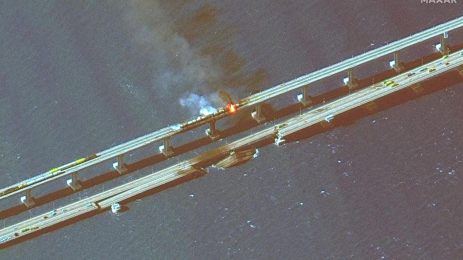 Gambar satelit menunjukkan asap mengepul dari kebakaran di jembatan Kerch di Selat Kerch, Crimea, Sabtu (8/10/2022). Jembatan yang menghubungkan Crimea dengan daratan Rusia itu hancur usai tangki berisi bahan bakar minyak (BBM) diduga meledak di lokasi itu dan menyebabkan 3 orang meninggal. (Maxar Technologies/Handout via REUTERS)