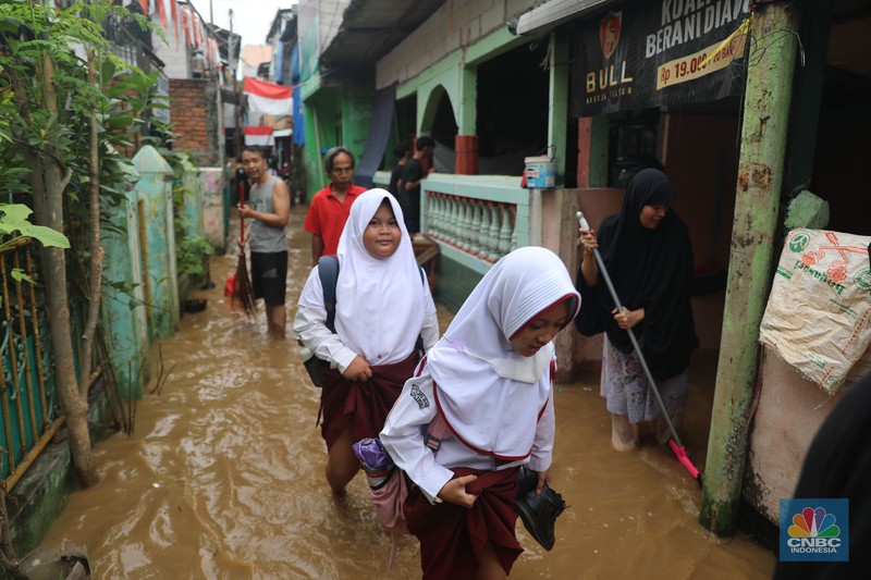 Petugas kepolisian mengevakuasi warga yang terkena banjir di kawasan Kebon Pala, Jakarta Timur, Senin, (10/10/2022). (CNBC Indonesia/Muhammad Sabki)