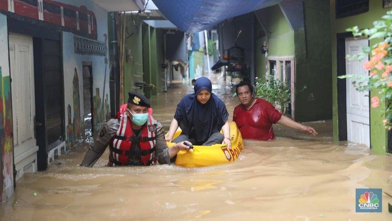 Petugas kepolisian mengevakuasi warga yang terkena banjir di kawasan Kebon Pala, Jakarta Timur, Senin, (10/10/2022). (CNBC Indonesia/Muhammad Sabki)