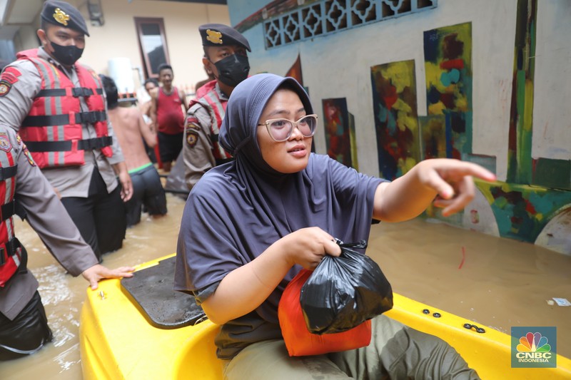 Petugas kepolisian mengevakuasi warga yang terkena banjir di kawasan Kebon Pala, Jakarta Timur, Senin, (10/10/2022). (CNBC Indonesia/Muhammad Sabki)