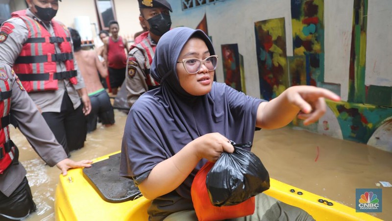 Petugas kepolisian mengevakuasi warga yang terkena banjir di kawasan Kebon Pala, Jakarta Timur, Senin, (10/10/2022). (CNBC Indonesia/Muhammad Sabki)