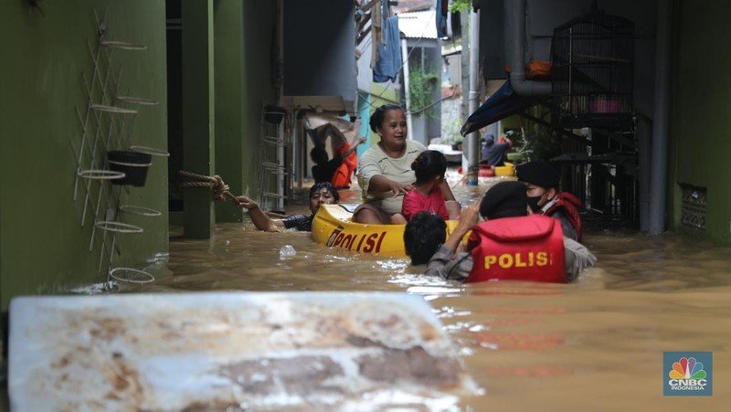 Petugas kepolisian mengevakuasi warga yang terkena banjir di kawasan Kebon Pala, Jakarta Timur, Senin, (10/10/2022). (CNBC Indonesia/Muhammad Sabki)