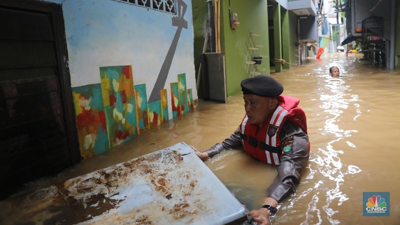 Petugas kepolisian mengevakuasi warga yang terkena banjir di kawasan Kebon Pala, Jakarta Timur, Senin, (10/10/2022). (CNBC Indonesia/Muhammad Sabki)
