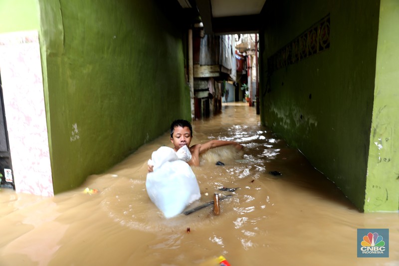 Petugas kepolisian mengevakuasi warga yang terkena banjir di kawasan Kebon Pala, Jakarta Timur, Senin, (10/10/2022). (CNBC Indonesia/Muhammad Sabki)