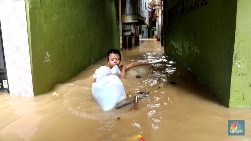 Petugas kepolisian mengevakuasi warga yang terkena banjir di kawasan Kebon Pala, Jakarta Timur, Senin, (10/10/2022). (CNBC Indonesia/Muhammad Sabki)