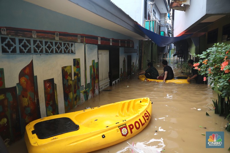 Petugas kepolisian mengevakuasi warga yang terkena banjir di kawasan Kebon Pala, Jakarta Timur, Senin, (10/10/2022). (CNBC Indonesia/Muhammad Sabki)