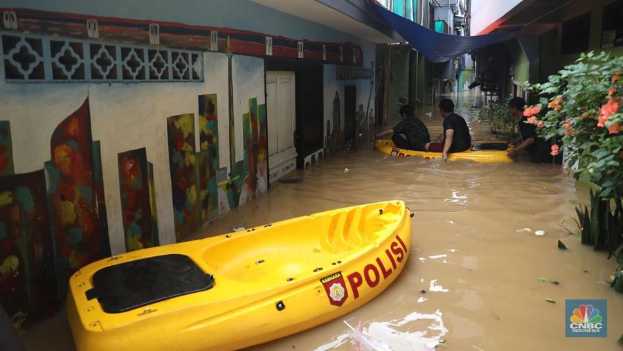 Petugas kepolisian mengevakuasi warga yang terkena banjir di kawasan Kebon Pala, Jakarta Timur, Senin, (10/10/2022). (CNBC Indonesia/Muhammad Sabki)
