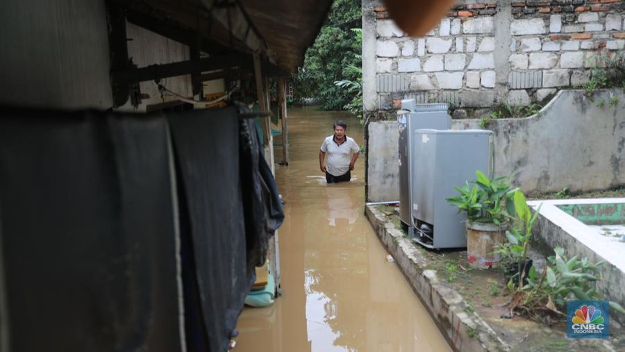 Warga melintas di kawasan banjir di Rawajati, Jakarta, Senin, (10/10). Banjir ini terjadi akibat luapan sungai Ciliwung. (CNBC Indonesia/Muhammad Sabki)