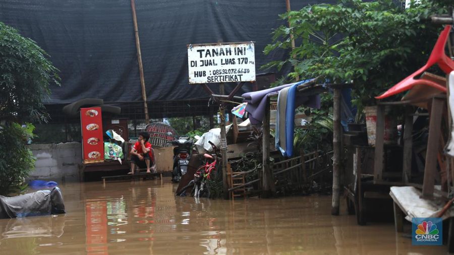 Warga melintas di kawasan banjir di Rawajati, Jakarta, Senin, (10/10). Banjir ini terjadi akibat luapan sungai Ciliwung. (CNBC Indonesia/Muhammad Sabki)